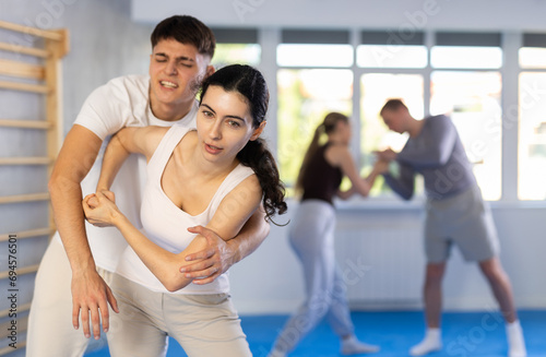 Woman practices blows to the head of a male attacker during self-defense training.