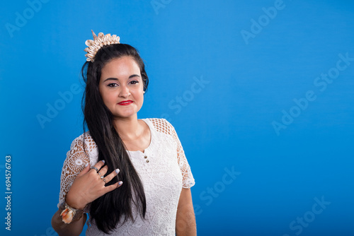 Beautiful young woman in white dress with shell tiara on her head looking at the camera. photo