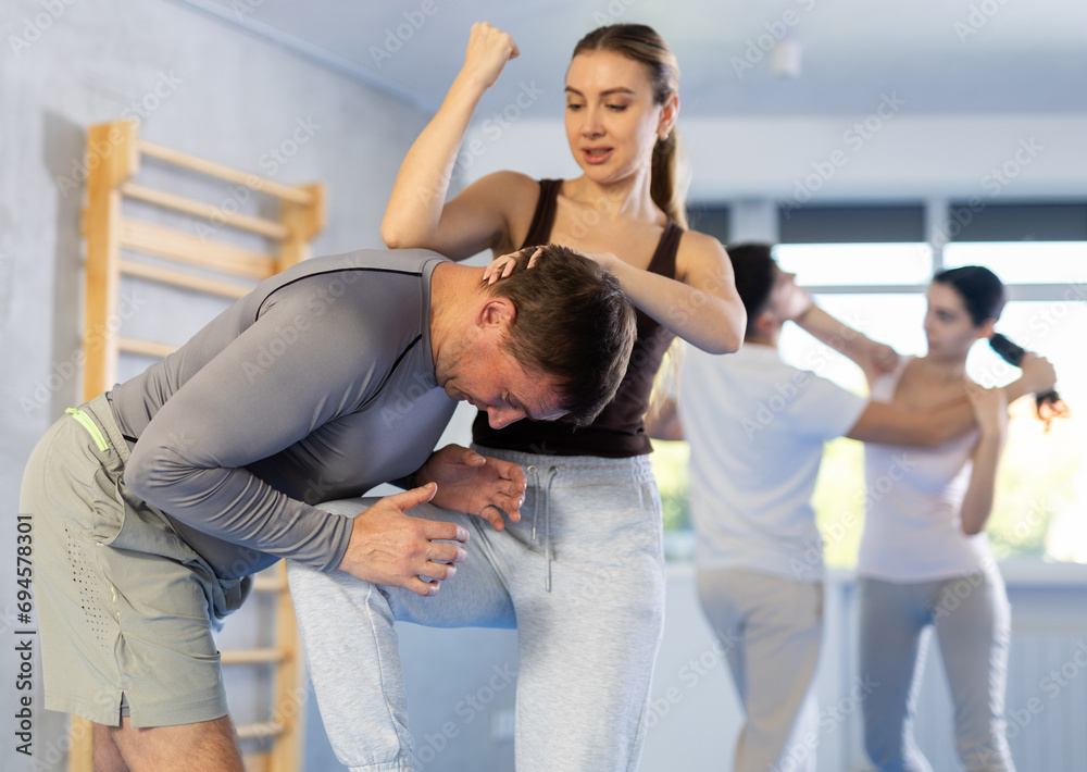Obraz premium Woman hits man attacker on head during self-defense training session led by a trainer