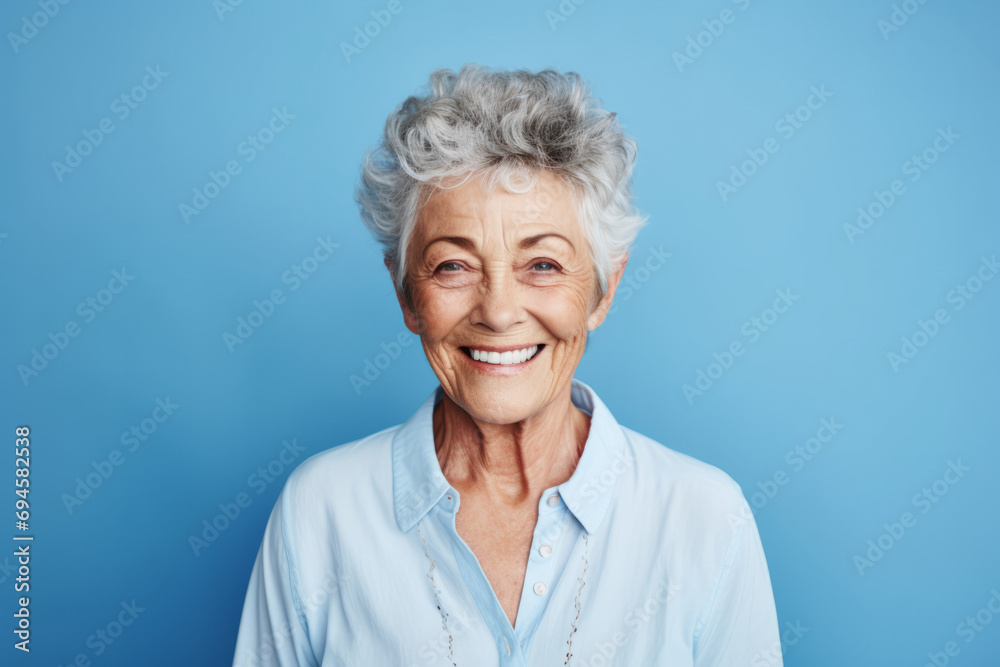 Portrait of happy senior woman smiling at camera on blue background. Portrait of happy senior woman smiling at camera on blue background.