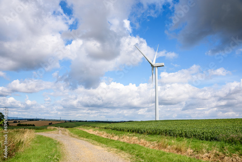 Wind turbine in a cultivated fieldd along a narrow gravel road in the English countryside on a sunny summer day photo