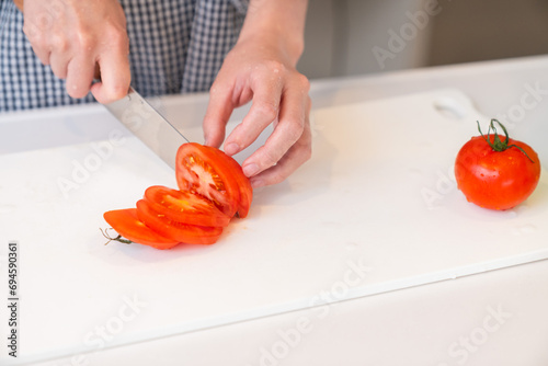 料理をする女性 手元 トマトを切る