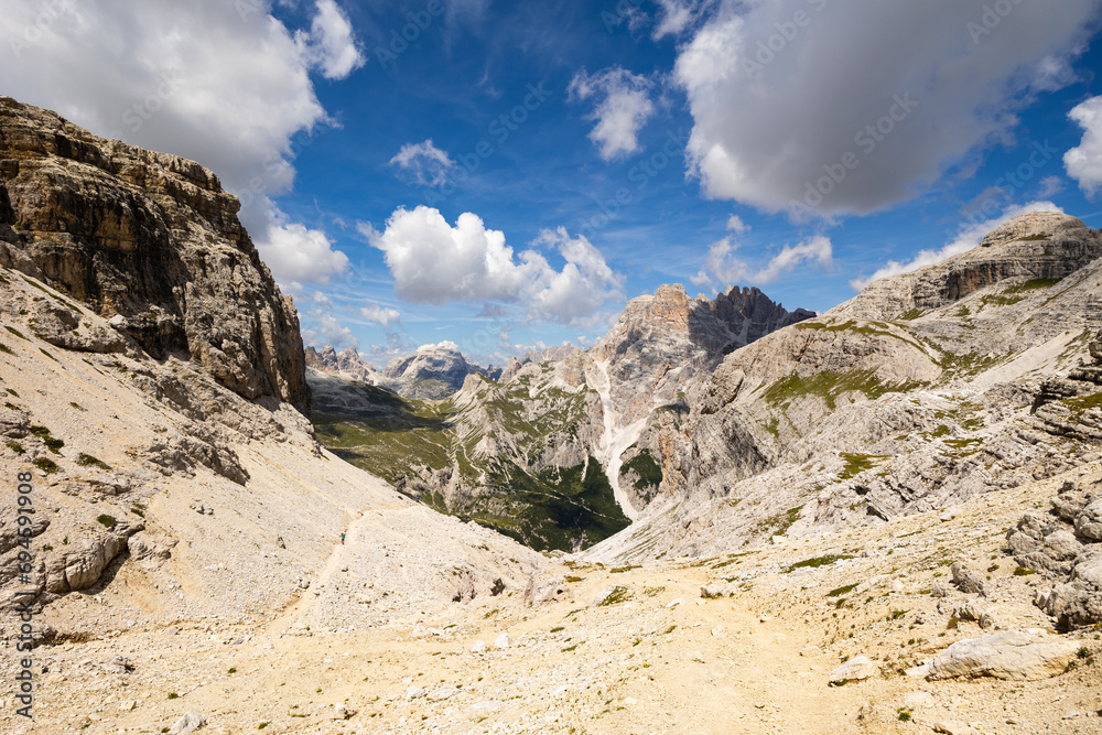 Rocks and mountain peaks of Dolomites against bright blue sky.