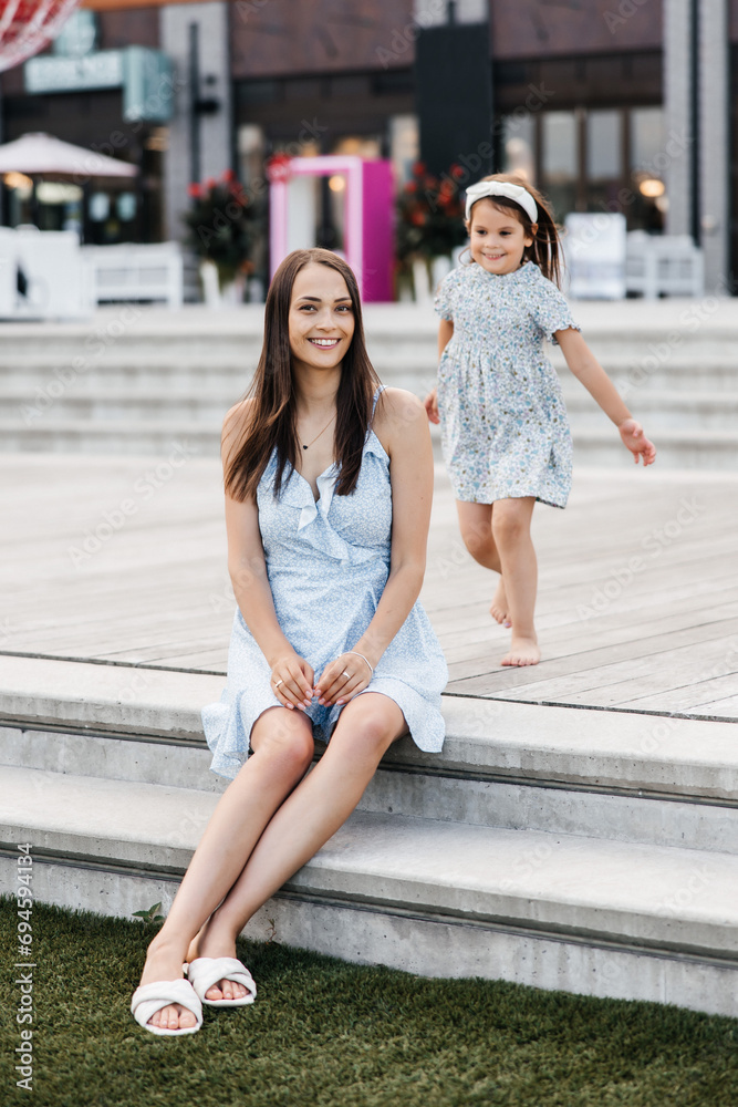 A young mother and her daughter are having fun outdoors. Mom and daughter spend time together. Happy childhood and motherhood. Happy family mother and daughter