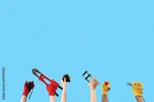 Female and male hands holding different construction tool on blue background