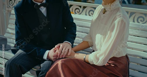 romantic date in 19th century, man and woman holding hands and sitting on bench in park, 4K, Prores photo