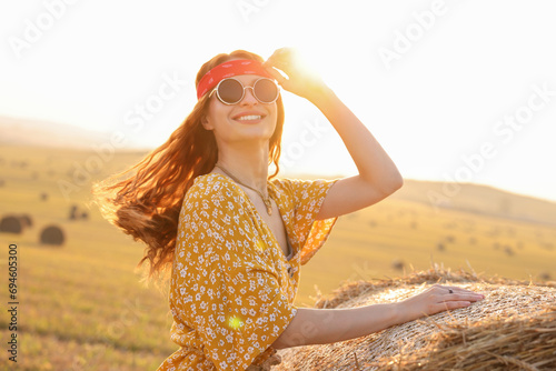Happy hippie woman near hay bale in field