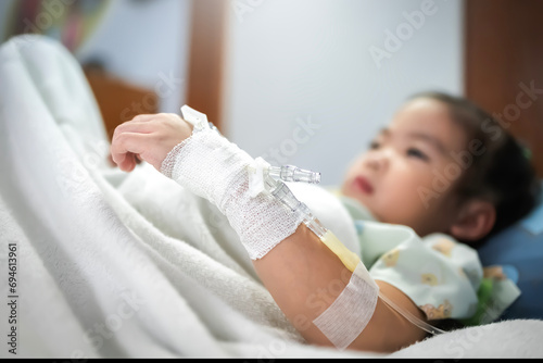 Little girl patient in hospital bed with saline intravenous (IV) photo