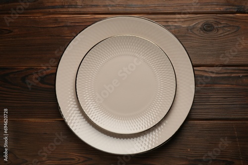 Beautiful beige ceramic plates on wooden table, top view