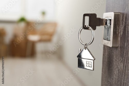 Mortgage and real estate. Open door with key and house shaped keychain against blurred background, space for text © New Africa