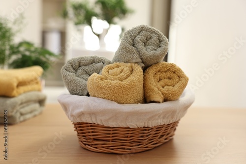 Basket with towels on wooden table indoors. Spa time
