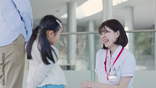 病院内にて話す笑顔の看護師と患者の子供