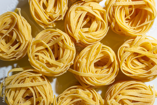 Uncooked Egg-Based Fettuccine Pasta: A Culinary Canvas of Ribbon-Shaped Macaroni, Creating a Lively and Textured Background for Gourmet Cooking. Dry Pasta. Raw Macaroni - Top View, Flat Lay