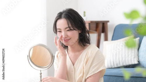 自宅で鏡でニキビやスキンケアや肌の調子をチェックしたり悩む若い女性の上半身の動画 photo