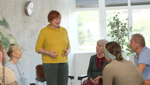 Mature female psychologist conducting a group session with mature clients Elderly female tutor teaching language to group of mature students woman photo