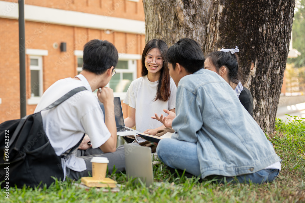Group of happy young teen Asian students are talking and doing homework in a campus park together. Group of happy young teen Asian students are talking and doing homework in a campus park together.