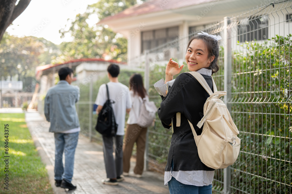 A smiling Asian female student is walking on a footpath on her campus, going to school.