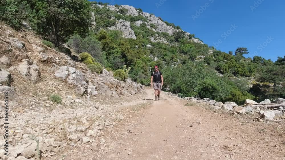 Man with backpack hiking on rocky mountain on dirt road on Lycian Way, Turkey Man with backpack hiking on rocky mountain on dirt road on Lycian Way, Turkey