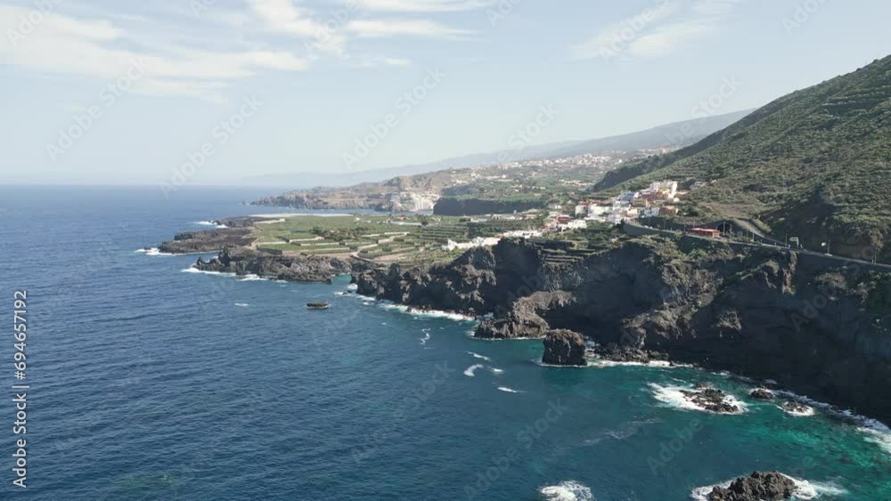 Rocky basalt cliffs raise bombarded by strong ocean waves with Tenerife in distance Rocky basalt cliffs raise bombarded by strong ocean waves with Tenerife in distance