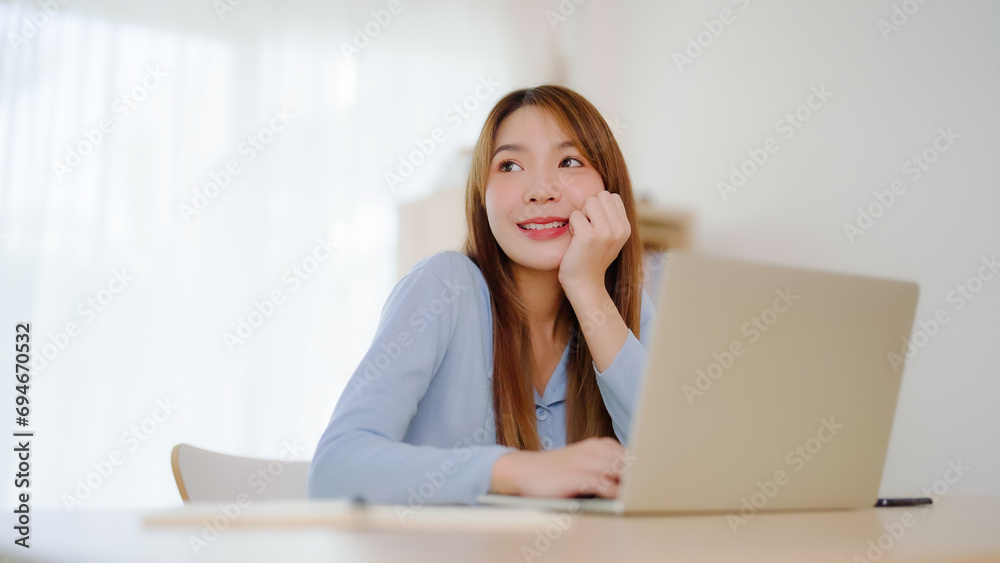 Young asian woman working at home. Happy female using computer laptop on desk at house Young asian woman working at home. Happy female using computer laptop on desk at house