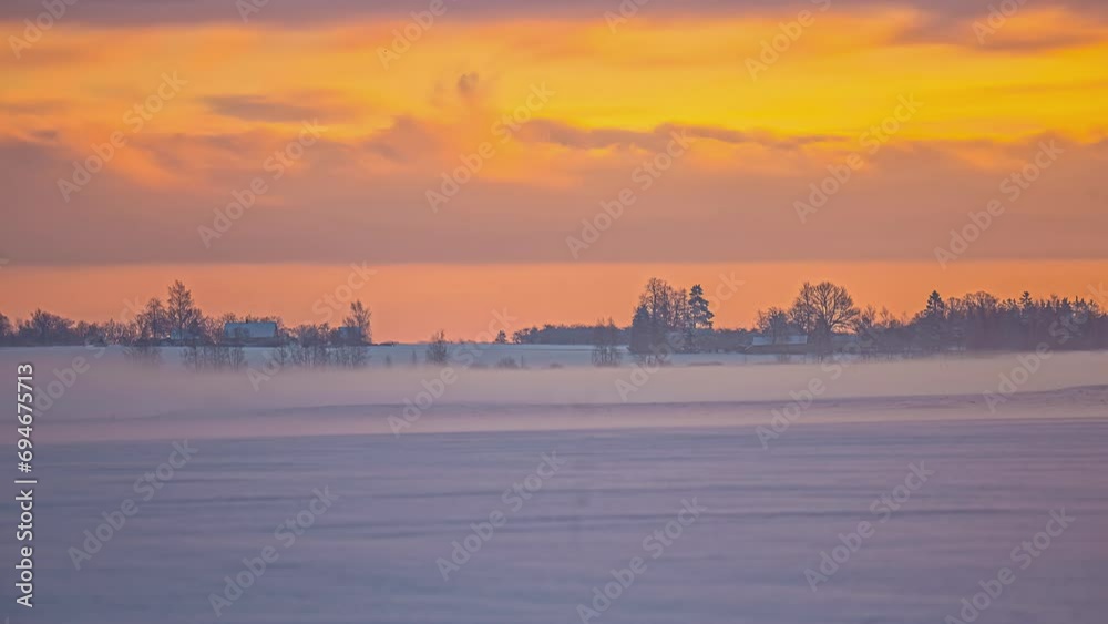 Winter rural time lapse moving clouds in golden sky in foggy morning, rural Latvia Winter rural time lapse moving clouds in golden sky in foggy morning, rural Latvia