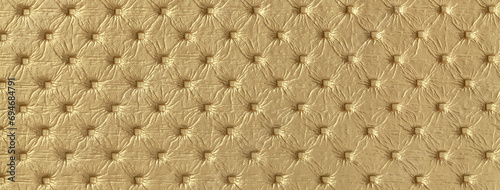 Texture of golden leather background with capitone pattern  macro. Yellow textile of retro Chesterfield style.