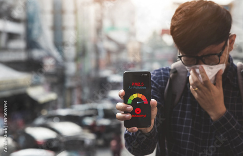Photography Asian man using a smartphone scanning the weather over smog city from PM2