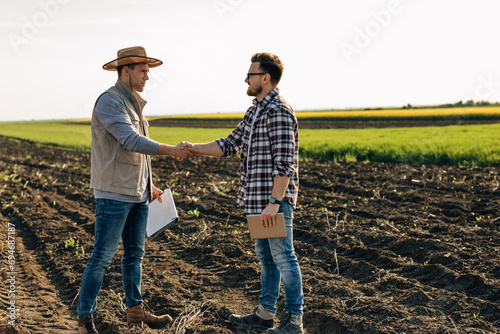 Agronomists shaking hands in the field.
