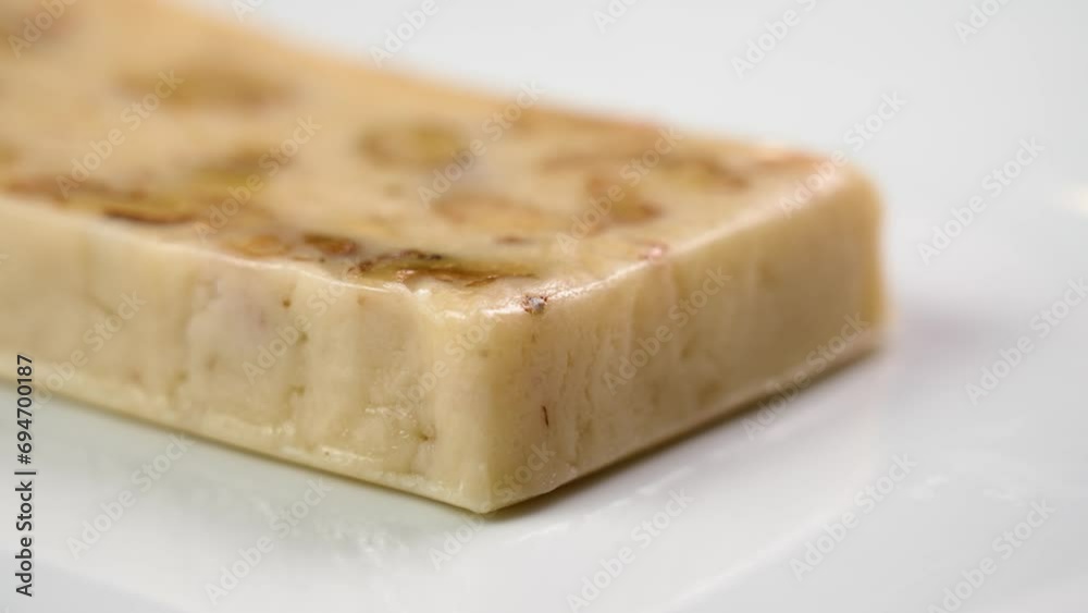 Traditional Spanish Christmas Turron with almond and nougat on a white ceramic dish close up. Rotation Traditional Spanish Christmas Turron with almond and nougat on a white ceramic dish close up. Rotation