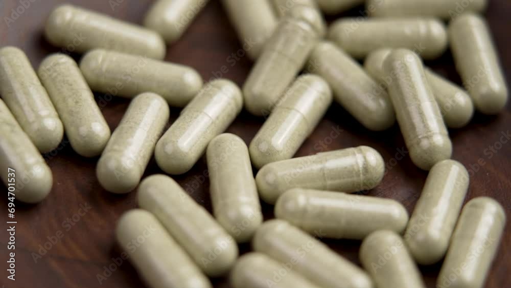 Herbal supplement vitamin capsules falling into a wooden bowl. Prescription natural pills. Herb medicine tablets Herbal supplement vitamin capsules falling into a wooden bowl. Prescription natural pills. Herb medicine tablets