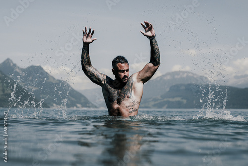 Sexy naked muscular Hispanic man splashing water in lake. Attractive male sexy model in water. Handsome boy rest in Alps lake water. Sexy man naked torso in water. Man freedom lifestyle. Strong photo