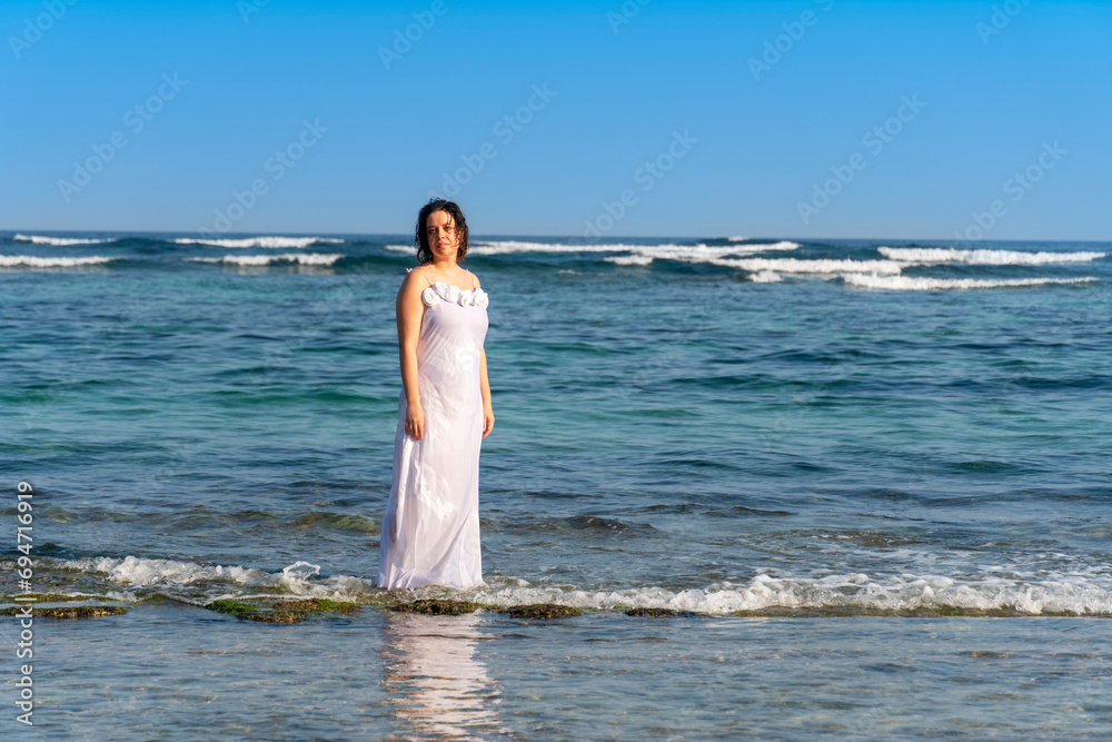 Beautiful woman in a white dress on the beach on a sunny day in summer. Beautiful woman in a white dress on the beach on a sunny day in summer.