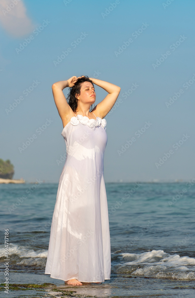 Portrait of a beautiful woman in white dress on the beach