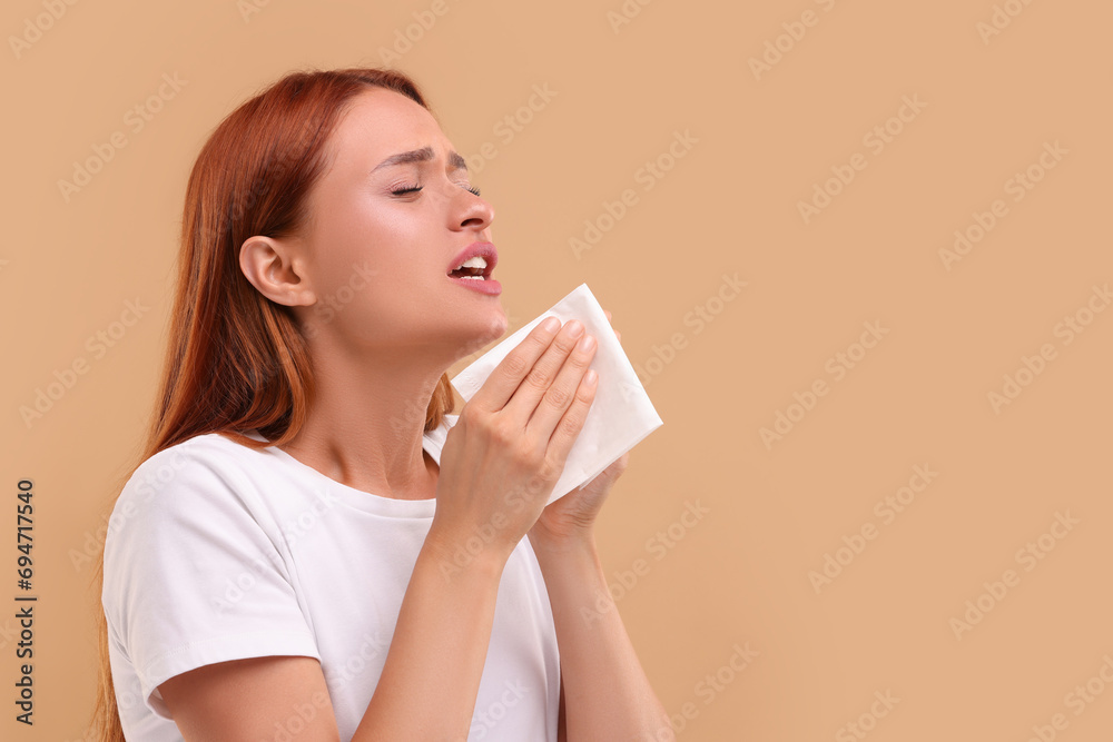 Suffering from allergy. Young woman with tissue sneezing on beige background, space for text Suffering from allergy. Young woman with tissue sneezing on beige background, space for text