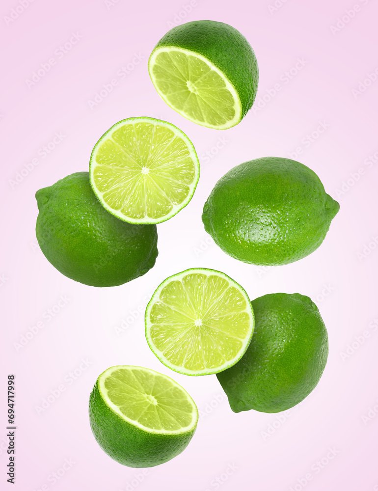 Fresh ripe limes falling on pale pink background