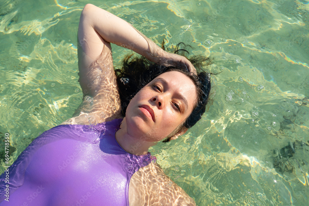 Portrait of woman relaxing in the ocean water on a hot summer day.