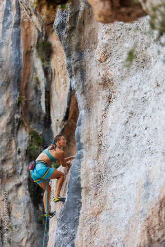 A young and strong woman is rock climbing on a rock.