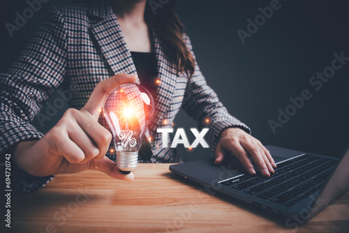 Businesswoman holding a light bulb tax icon for individuals and companies paying tax rates. Effective tax deduction planning, prepare reduction, calculate payments, refund concept.