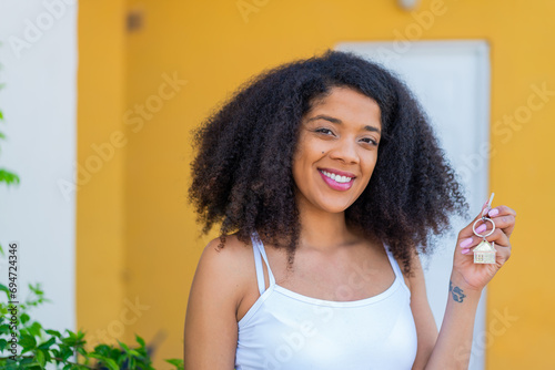 Young African American woman holding home keys at outdoors smiling a lot