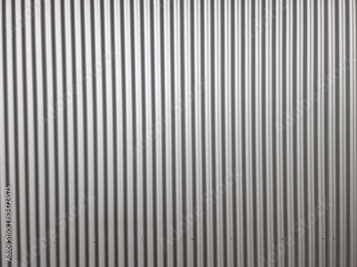 building is lined with square panels. metal sheet wall cladding with scalloped design. corrugated sheet, dark gray, riveted. horizontal stripes, shadows, corner, fence, aluminium, sheet
