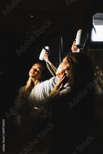 Sexy woman blow drying her hair after shower.Personal hygiene concept © Darius