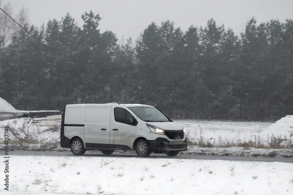 The importance of winter tires for a car on a slippery road. a snowy and frosty landscape in the background. Side view of a moving car in the winter.