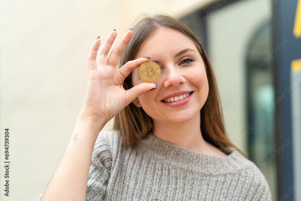 Young pretty blonde woman holding a Bitcoin with happy expression Young pretty blonde woman holding a Bitcoin with happy expression