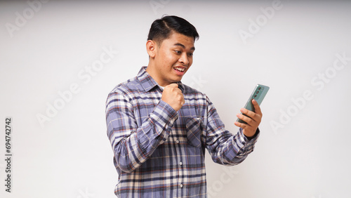 Asian man holding mobile phone showing enthusiastic expression photo