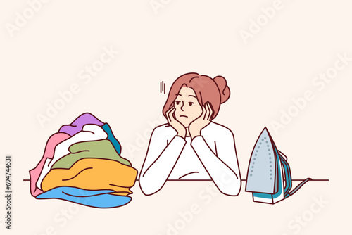 Pensive woman housewife sits near ironing board and iron, reflecting on lack of personal development. Housewife girl needs rest to recuperate and treat depression associated with burnout.