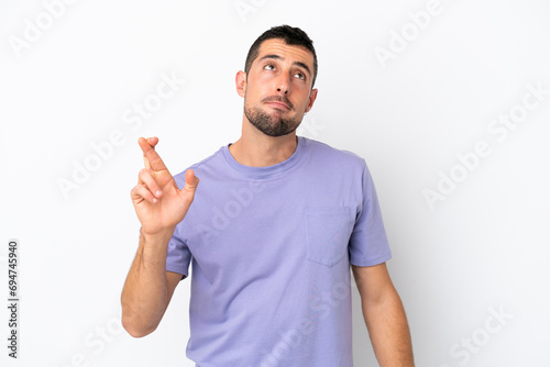 Young handsome caucasian man isolated on white background with fingers crossing and wishing the best