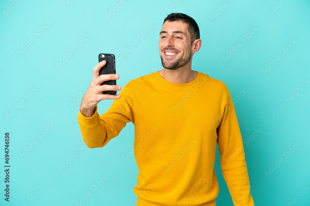 Young handsome caucasian man isolated on blue background making a selfie Young handsome caucasian man isolated on blue background making a selfie