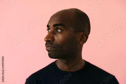 Man with shaved head against pink background photo