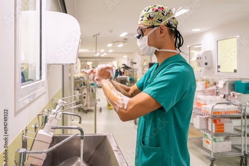 Surgeon wearing mask washing hands in hospital photo