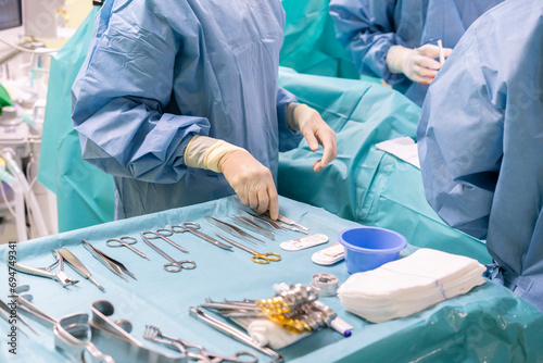 Nurse holding surgical tool with surgeons performing surgery on patient in emergency room photo